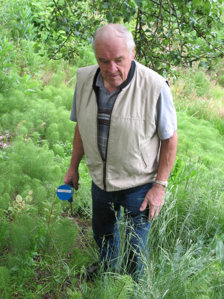 Joe Cindrich holding a syringe & searching for Japanese Knotweed